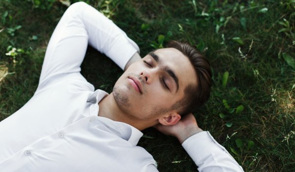 Handsome young man in a white shirt lies on the ground
